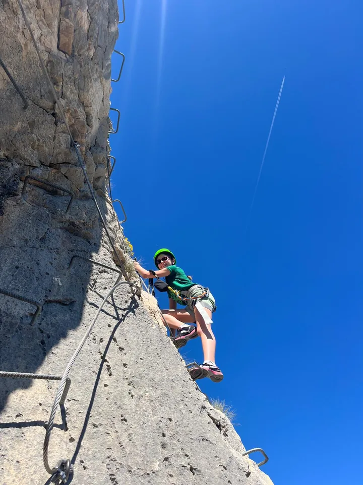 Young climber on a protected rock route high above Provence scenery.
