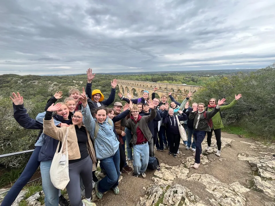 Large hiking group gathered above the Pont du Gard aqueduct.